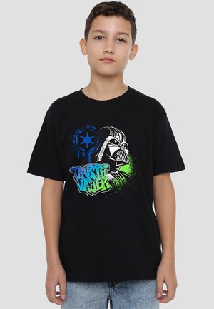 Schwarzes Baumwoll-T-Shirt mit einem grafischen Druck eines Charaktergesichts in Weiß, verziert mit blauen und grünen Farbspritzern sowie stilisiertem Text.