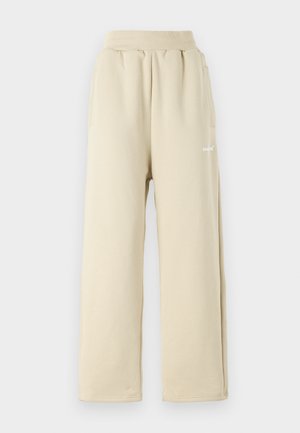 Beige vide ben bukser laget av myk stoff, med elastisk midje, sidelommer og små broderte logo detaljer.