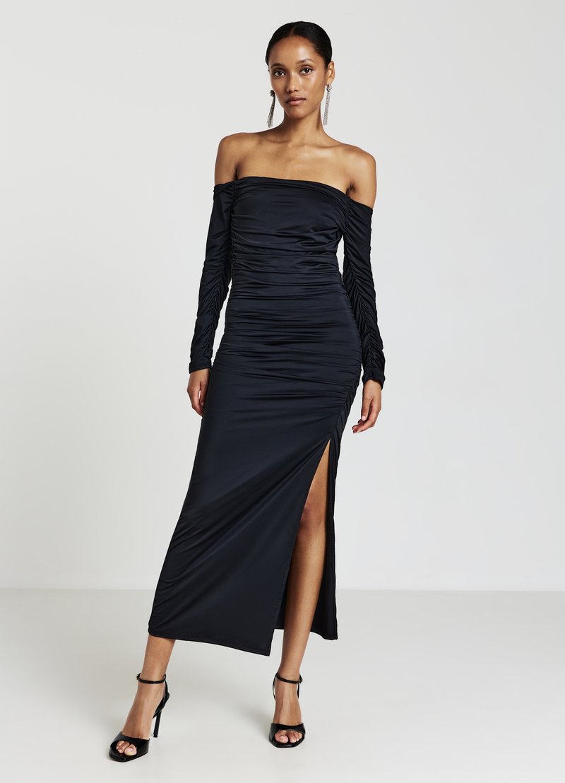 Abito nero off-the-shoulder con lunghe maniche arricciate, una silhouette aderente e un alto spacco laterale, realizzato in un tessuto morbido e elasticizzato.