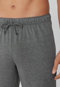Pantalones de lounge grises de jersey con una cinturilla elástica y cordón. Tejido texturizado con un acabado suave, diseñados para la comodidad.