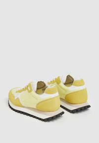 Gula sneakers med överdel i mocka och syntet, vita detaljer, vadderad krage och svart gummisula med mönstrat grepp.