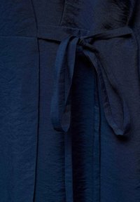 Tmavě modré šatové šaty s texturou a jemným leskem, se zavazovacími pásky v  pase a sklady pro větší designový efekt.