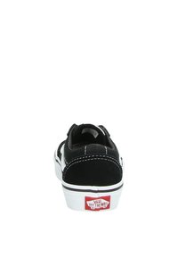 Sneaker in suede nera con accenti bianchi, dotata di collo imbottito, cuciture a contrasto e logo Vans rosso sul tallone. Design classico low-top.