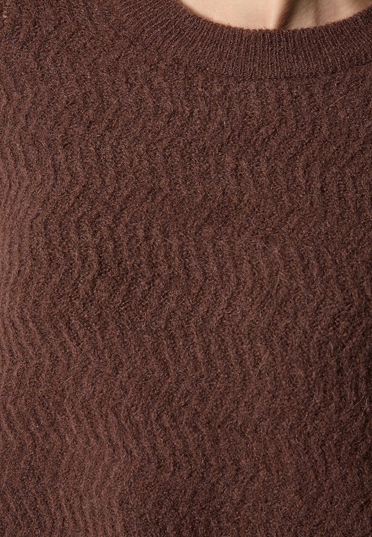 Brauner gestrickter Pullover mit einem strukturierten Zickzackmuster, ausgestattet mit einem Rundhalsausschnitt und weichem, flauschigem Material.