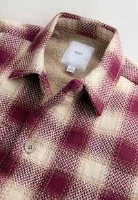 Geruit overhemd met een bordeauxrode en crèmekleurige patroon, gemaakt van een gestructureerde stof met een knoopsluiting en een zachte fleecevoering.