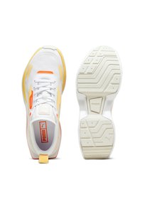 Baskets blanches de sport avec des accents jaunes et oranges, tige en tissu en maille, semelle texturée avec des motifs de traction et un logo Puma bien en vue.