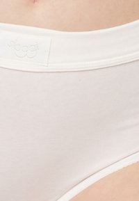 Weiße Baumwollunterhose mit einem weichen, elastischen Bund, der ein kleines Logo-Täfelchen trägt. Glatte Textur und klassisches Design mit voller Bedeckung.