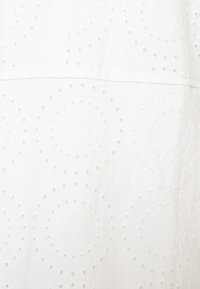 White fabric featuring tonal circular embroidery with open cutouts. Soft texture, smooth surface, lightweight appearance, and subtle design.