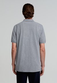 Grijze polo met korte mouwen, geribbelde kraag en een rechte zoom. Zachte stoftextuur, minimalistisch ontwerp zonder patronen of accenten.