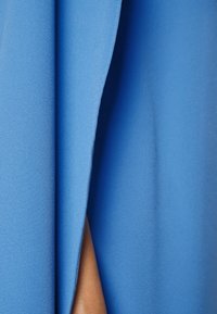 Blue fabric drapes softly, showing a smooth texture and slight sheen. The design features clean edges with a subtle seam detail.