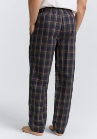 Pantalons de pyjama à carreaux avec taille élastique, présentant une base vert foncé et un motif écossais multicolore. Comprend des poches latérales.