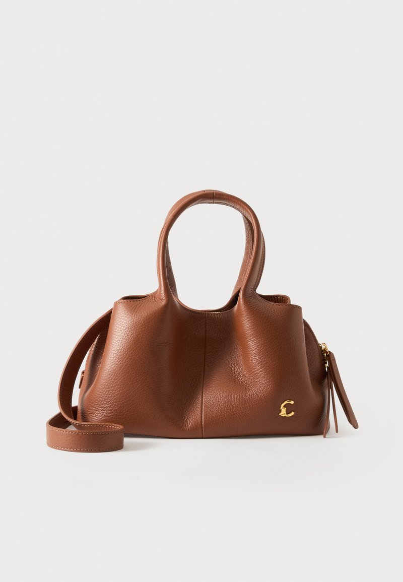Sac à main en cuir marron avec deux anses supérieures, une bandoulière amovible et un petit logo doré "C" sur un fond clair.