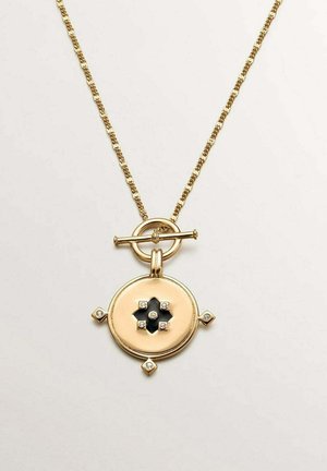 Collar de cadena dorada con colgante redondo que presenta un diseño negro de cuatro pétalos y pequeños acentos de diamantes en los bordes y el centro.