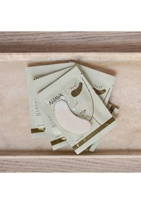 AHAVA ögonmask i vit och guldfärgad förpackning med illustrationer av ögon. Fem individuella paket utfällda på en ljus marmoryta.