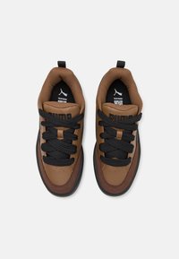 Baskets en cuir marron avec lacets noirs, col rembourré et semelle en caoutchouc noire. Logo Puma sur le côté et semelle intérieure rembourrée.