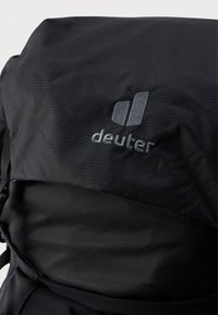 Must mustkott, millel on tekstureeritud pind ja hallitud kujutatud "deuter" logo. Disain on voolujooneline ja reguleeritavad rihmad.