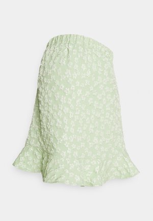 Saia floral verde com um padrão texturizado, cintura elástica e bainha em babados. Apresenta pequenas flores brancas por todo o tecido.