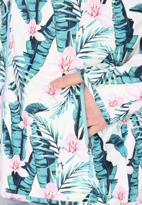 Langærmet bluse med et livligt blomster- og bladbillede i nuancer af blå og pink, med en lynlåsdetalje på ærmet.