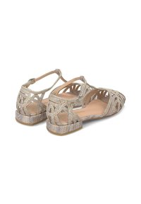 Sandales dorées scintillantes avec un design ouvert, des motifs découpés et un petit talon block. Le matériau a une texture lisse avec une finition métallique.