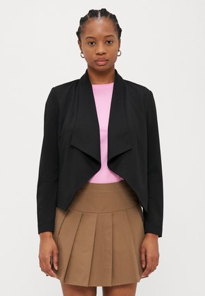Svart, skreddersydd, asymmetrisk jakke med drapert frontdesign, sammen med en rosa topp og et plissert brunt skjørt. Glatt tekstur, ingen synlige detaljer.