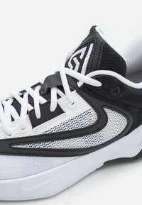 Juoda ir balta sportinė kedai su tinkline medžiaga, baltais raišteliais ir Nike swoosh logotipu ant pado, rodomas artimu šoniniu vaizdu.
