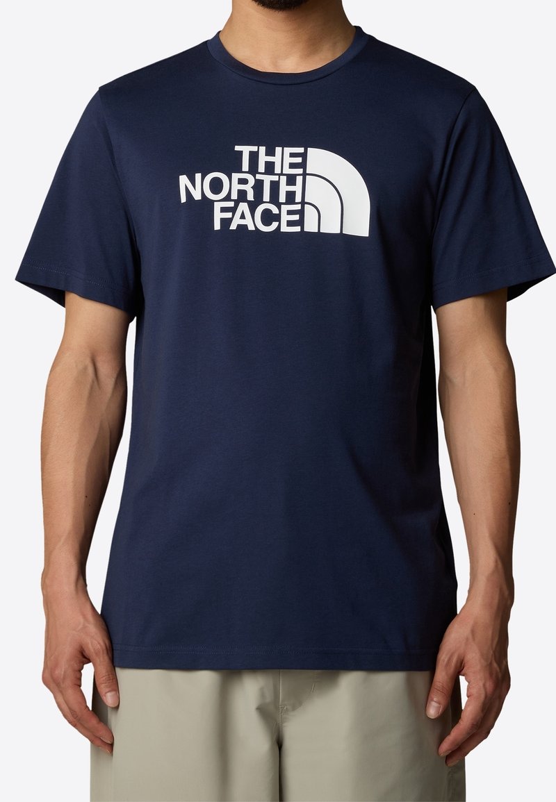 Navy blue cotton t-shirt featuring a white logo text and curved graphic. Short sleeves and round neckline with a smooth texture.