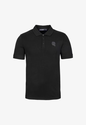 Camiseta polo negra de manga corta, con tapeta de tres botones, cuello acanalado y un discreto acento de logo en el pecho. Material de algodón suave.