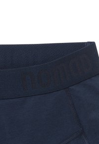 Navy blue men's underwear with a textured waistband featuring the word "nomad" in black and contrasting stitching along the seams.