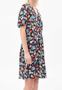 Robe florale avec un fond noir, des manches courtes bouffantes, un décolleté en V, et un motif de fleurs multicolores en rouge, bleu et vert.