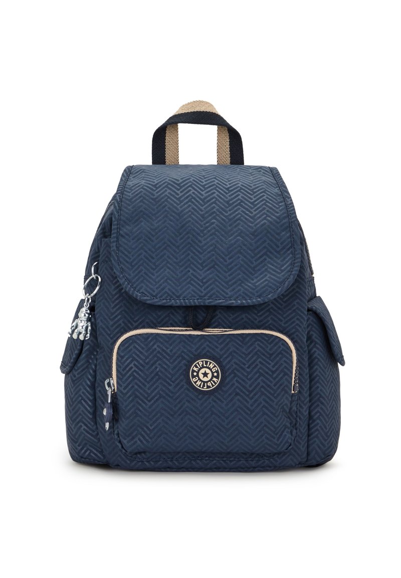 Sac à dos bleu marine avec motif en chevrons, poche avant zippée, poches latérales, poignée de transport beige et noire, et un porte-clés singe en argent.