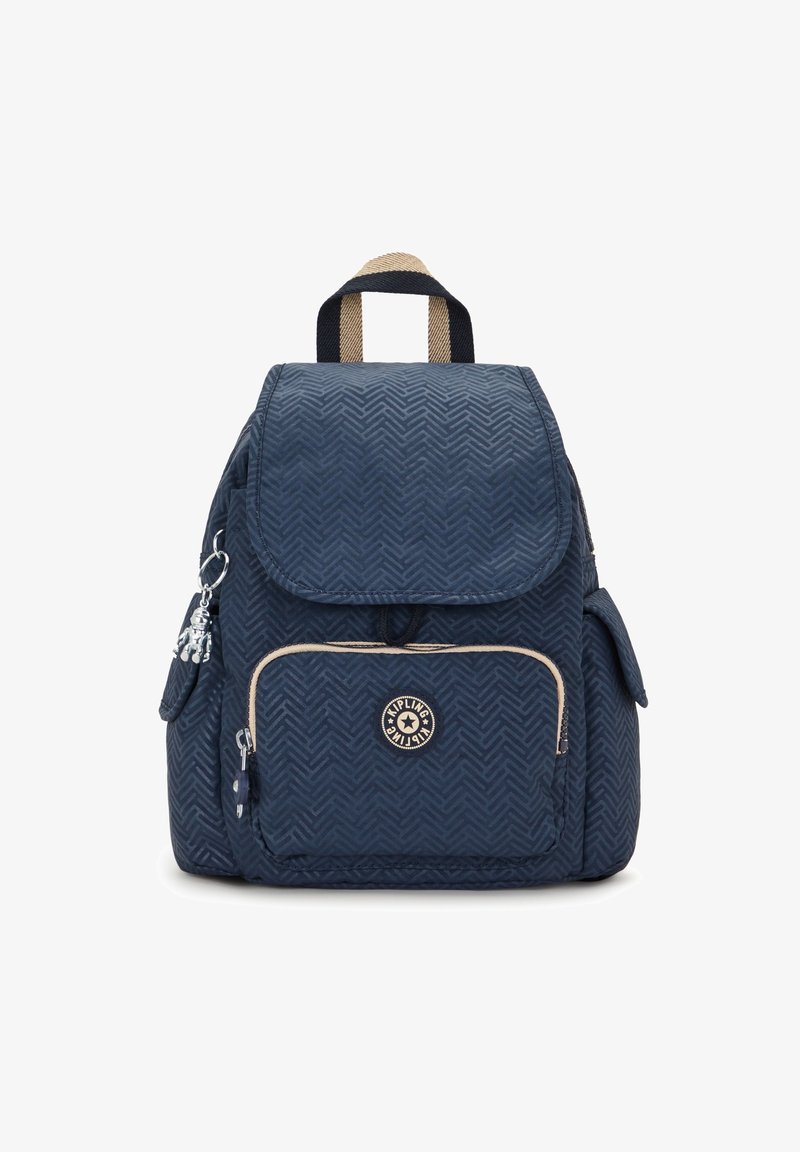 Sac à dos bleu marine avec motif en chevrons, poche avant zippée, poches latérales, poignée de transport beige et noire, et un porte-clés singe en argent.