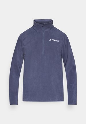 Temno modra flis pulover s polovičnim zadrgo ovratnikom, z belo nalepko "TERREX" na prsih in dolgimi rokavi. Gladek tekstura.
