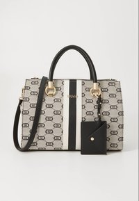 Sac à main beige et noir à motifs avec deux poignées noires, rayures verticales noires et blanches, ferrures dorées, bandoulière détachable et petite pochette noire.