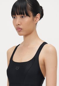Schwarze Badebekleidung mit quadratischem Ausschnitt und breiten Trägern. Glattes Material mit dezentem Branding; einfaches, funktionales Design ohne Verzierungen.
