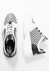 Baskets mode avec un motif damier blanc et noir, accents en cuir texturé, semelles blanches épaisses et lacets noirs.