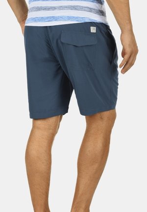 Herren-Shorts in Marineblau aus leichtem Stoff. Mit Gesäßtasche und Klappe. Glatte Textur, legeres Design, knieumspielende Passform.