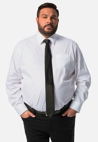 Biała koszula z długim rękawem z kieszonką na piersi, zestawiona z czarnym krawatem. Czarny pasek z srebrną klamrą. Czarne spodnie.