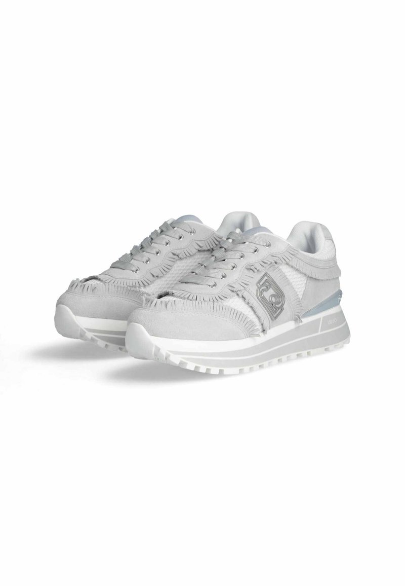 Helle graue Sneakers aus strukturiertem Material mit ausgefransten Kanten und einem reflektierenden Akzent. Sie verfügen über ein Schnürdesign und eine klobige weiße Sohle.