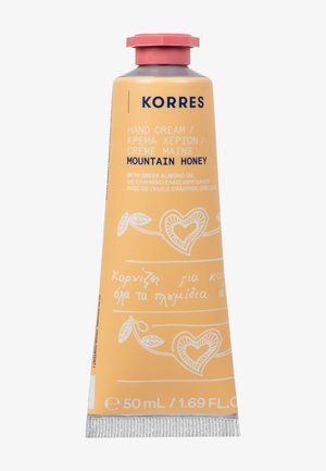 Tubo de crema de manos Korres con un diseño amarillo-naranja, material de aluminio, tapa rosa e ilustraciones blancas, etiquetado "Miel de Montaña". 50 mL.