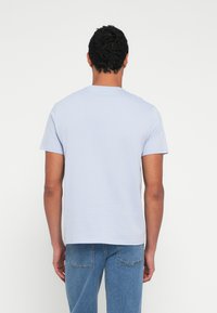 Hele sinine lühikeste varrukatega T-särk ümarate kaelustega, valmistatud pehmest puuvillast. Lihtne disain, sirge lõige, ilma nähtavate mustrite või aksentideta.