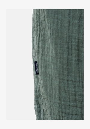 Groene textuurstof met een gekreukt ontwerp, met een klein label waarop "SEASIDE" in marineblauw staat.