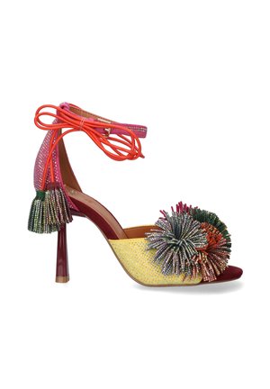 Sandalia de tacón alto con pompones multicolor brillantes, paneles amarillos y rosas con purpurina, correa roja atada al tobillo y detalles de borlas en el talón.