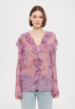 Zijdeachtige roze blouse met gerafelde randen en bloemenpatronen, met een V-hals en lange mouwen. Gecombineerd met lichtblauwe denim jeans.