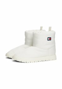 Botas de tobillo acolchadas blancas con una superficie texturizada, que presentan un parche con el logo y tiradores en la parte superior. Suelas de goma gruesas y con relieve para mayor agarre.