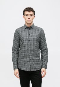 Fekete-fehér kockás hosszú ujjú ing gallérral gombos rögzítéssel és elején gombokkal, szövött anyagból készült. Lapos szabású, polírozott textúrával.