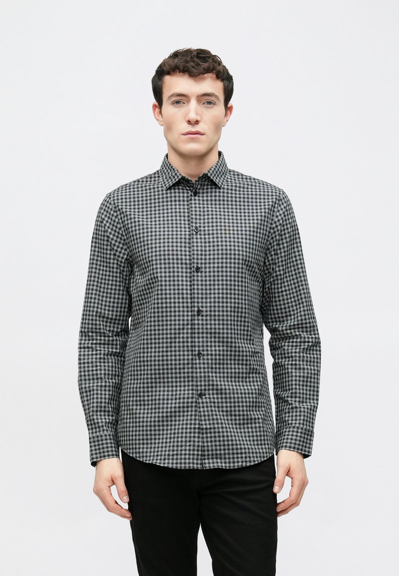 Fekete-fehér kockás hosszú ujjú ing gallérral gombos rögzítéssel és elején gombokkal, szövött anyagból készült. Lapos szabású, polírozott textúrával.