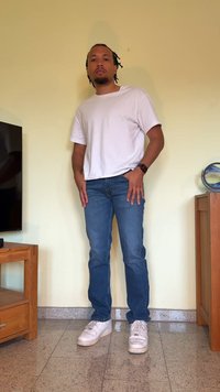 Camisa branca de manga curta, jeans azuis e ténis brancos. A camisa é simples, os jeans são ajustados e os ténis têm um design texturizado.
