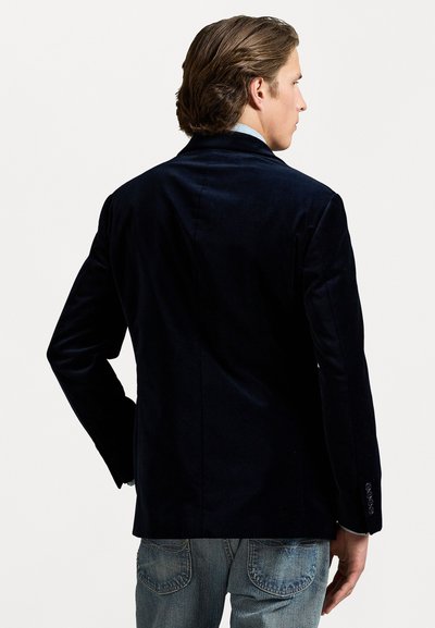 Námořnický sametový blazer s přizpůsobeným střihem, jednoramenným rozparkem a jemným leskem. Obsahuje dlouhé rukávy s knoflíkovými manžetami a klasický límec.