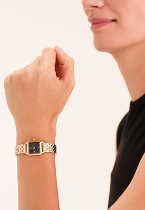Reloj cuadrado en tono dorado con esfera negra, pulsera de metal plateado, que presenta un diseño minimalista y tres pequeños acentos en el dial.