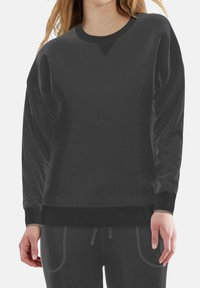 Felpa nera a maniche lunghe con scollatura tonda e polsini a coste. Realizzata in materiale morbido, presenta una vestibilità ampia e una leggera texture.